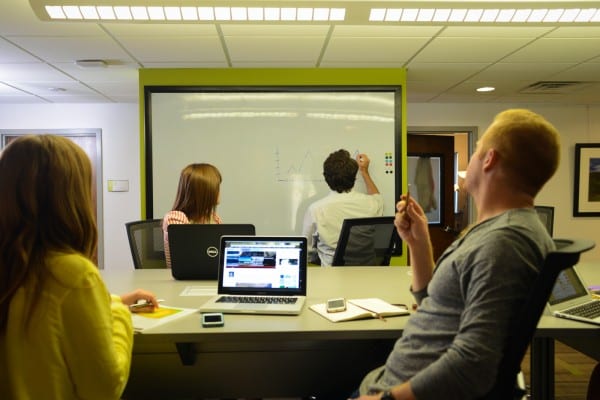 Four people looking at projector.