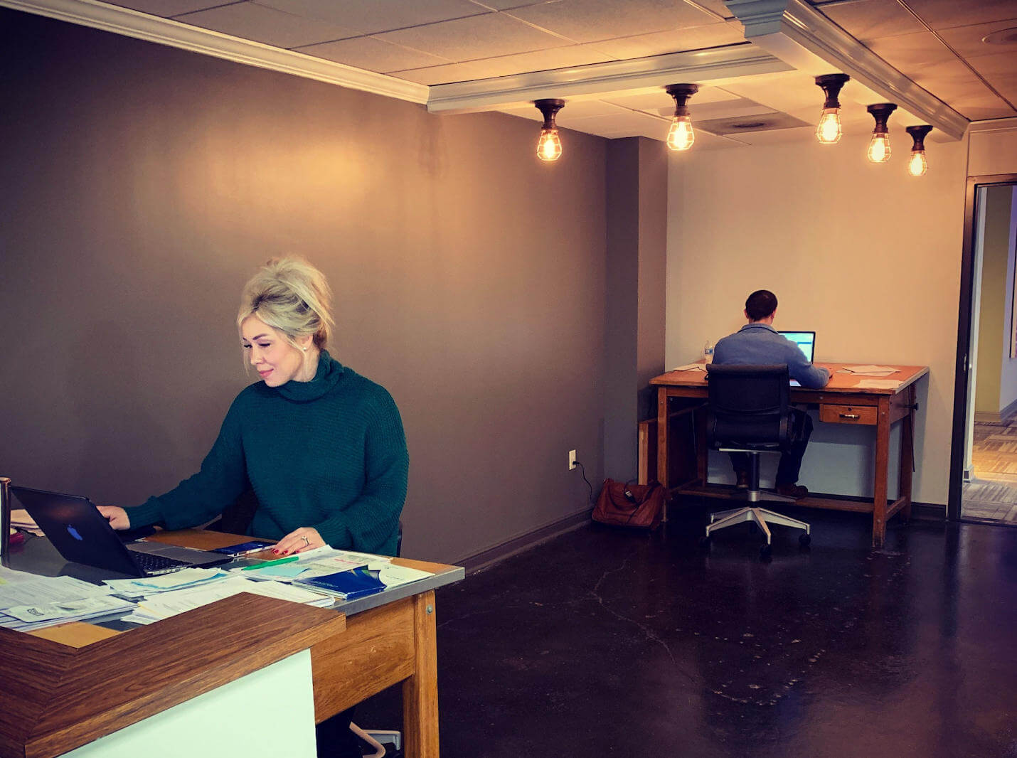Woman and man working at two desks in a coworking space.