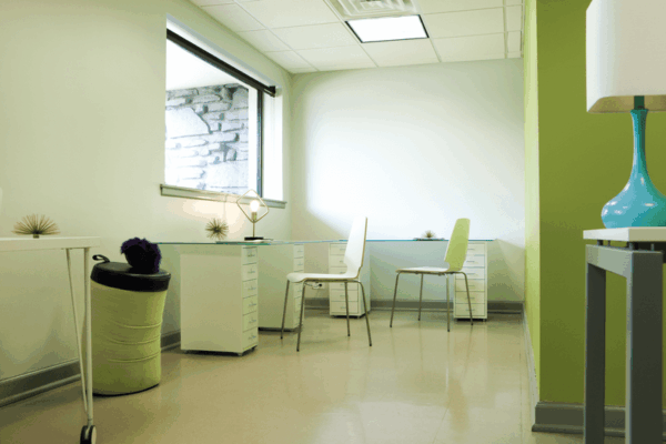 An office with light green walls, desk, and window.
